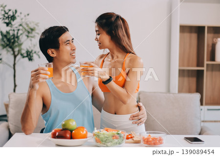 A happy couple prepares fresh vegetables, laughing and enjoying cooking a healthy meal together. 139089454