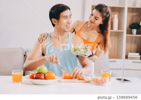 A happy couple prepares fresh vegetables, laughing and enjoying cooking a healthy meal together. 139089456