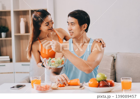 A happy couple prepares fresh vegetables, laughing and enjoying cooking a healthy meal together. A happy couple prepares fresh vegetables, laughing and enjoying cooking a healthy meal together. 139089457