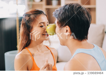 A happy couple prepares fresh vegetables, laughing and enjoying cooking a healthy meal together. 139089464
