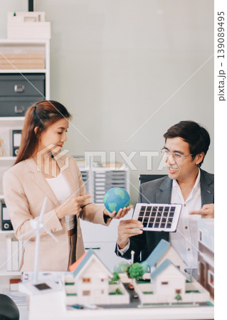 Real Estate Broker discussing with a customer model install solar roof house modern project in the office, real estate developer alternative energy, development business sustainable, zero energy, ESG. 139089495