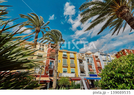 Colorful houses and buildings of Villajoyosa with palm trees against backdrop blue sky at sunny day Colorful houses and buildings of Villajoyosa with palm trees against backdrop blue sky at sunny day 139089535