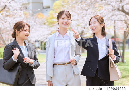 桜並木の下で笑顔で会話するリクルートスーツ姿の女性3人・春の就職活動イメージ 桜並木の下で笑顔で会話するリクルートスーツ姿の女性3人・春の就職活動イメージ 139089633