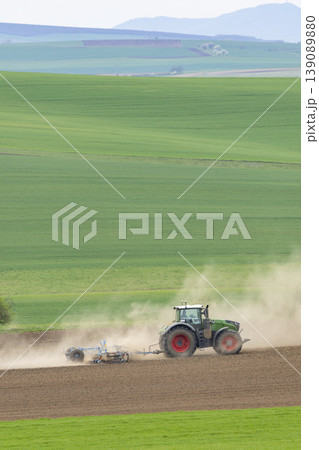 Farming tractor cultivating field creating dust in Svatoborice Mistrin 139089880