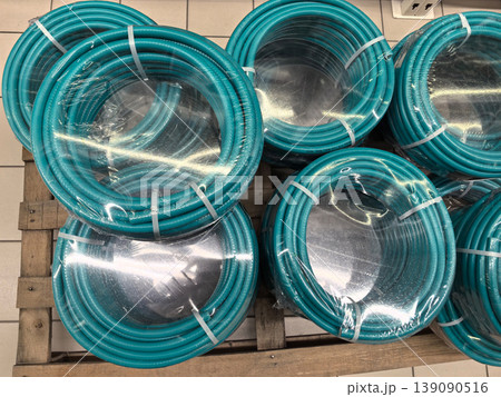 Colorful turquoise garden hoses neatly arranged for sale in a store Colorful turquoise garden hoses neatly arranged for sale in a store 139090516