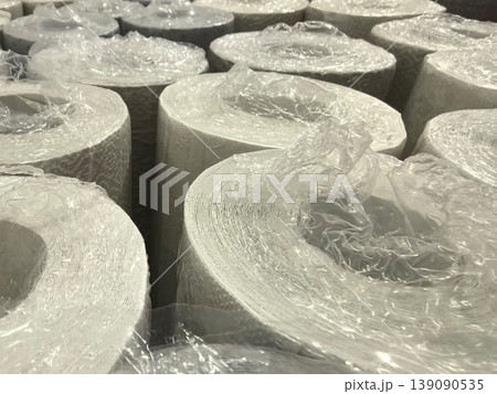 Rolls of white paper wrapped in plastic stacked in a warehouse Rolls of white paper wrapped in plastic stacked in a warehouse 139090535