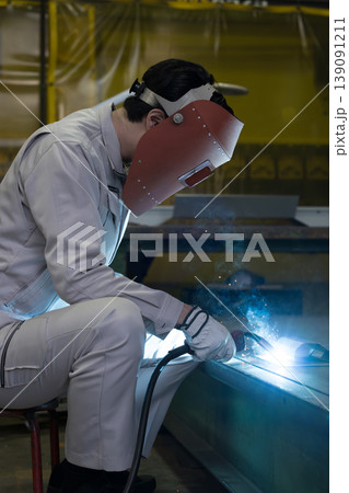 製造業の工場でアーク溶接作業を行う溶接ヘルメットをつけた作業員のものづくり現場と技術 製造業の工場でアーク溶接作業を行う溶接ヘルメットをつけた作業員のものづくり現場と技術 139091211
