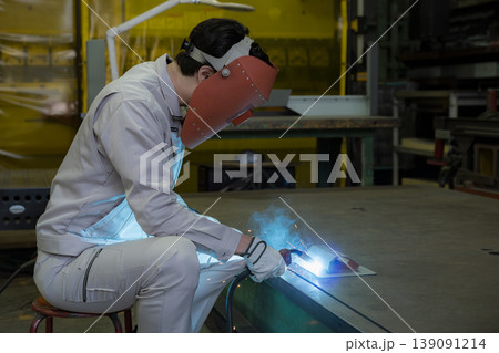 製造業の工場でアーク溶接作業を行う溶接ヘルメットをつけた作業員のものづくり現場と技術 139091214