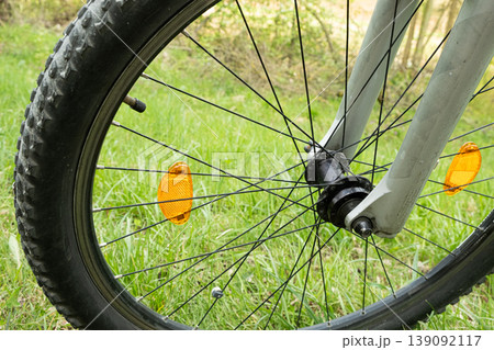 Close-up of a bicycle wheel with yellow plastic reflectors. 139092117