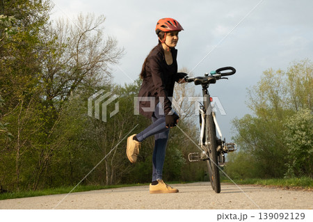 Female cyclist stopped on a path holding her pained knee, sport injury concept 139092129