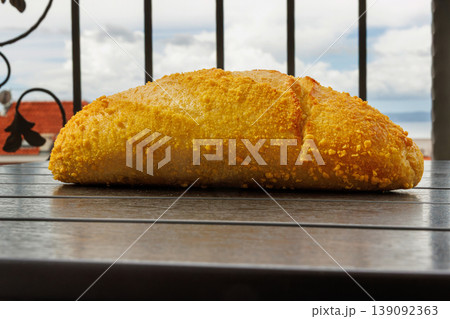 Croatian corn bread loaf on a balcony table with a view on Adriatic sea and rooftops in Makarska, Croatia in blurred background. Selective focus 139092363