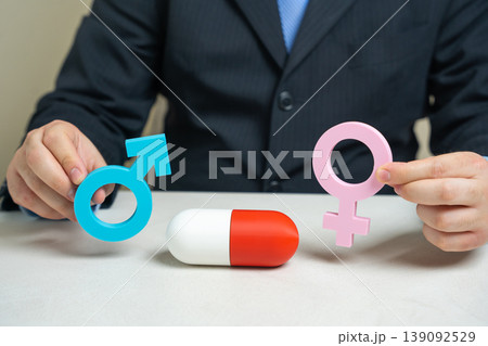 Figures of a man and woman with a pill capsule between them Figures of a man and woman with a pill capsule between them 139092529