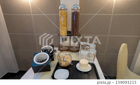 Cereals in the cereal serving containers and milk in the pitcher on the table 139093215