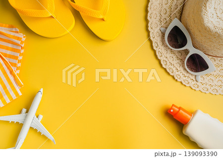 Summer background. Sunglasses, beach flip-flops, sunscreen, sun hat and airplane. Yellow background with copy space. Summer background. Sunglasses, beach flip-flops, sunscreen, sun hat and airplane. Yellow background with copy space. 139093390
