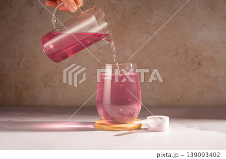 Pink food supplement powder in glass of water. Collagen, protein powder, vitamins. Pink food supplement powder in glass of water. Collagen, protein powder, vitamins. 139093402