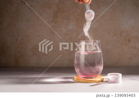 Pouring food supplement powder in glass of water. Collagen, protein powder, vitamins. Pouring food supplement powder in glass of water. Collagen, protein powder, vitamins. 139093403