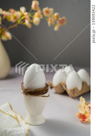 Easter spring background. Egg in ceramic egg holder, stand. Eggs box with flowers. Minimalistic 139093422