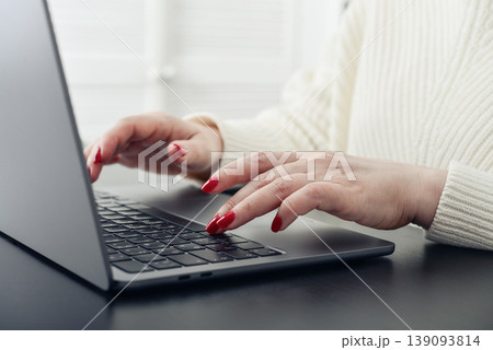 Close up of female hands with red manicure typing on a laptop keyboard. Close up of female hands with red manicure typing on a laptop keyboard. 139093814