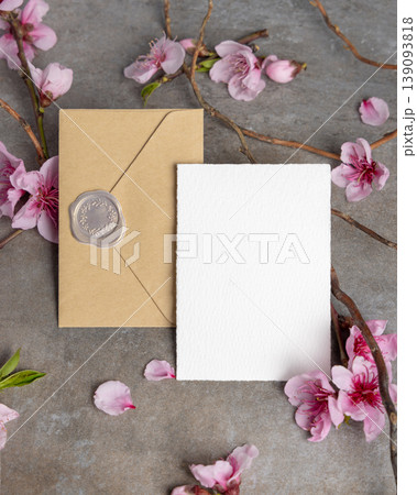 Spring wedding blank card and envelope mockup with pink cherry blossoms and twigs on grey stone 139093818