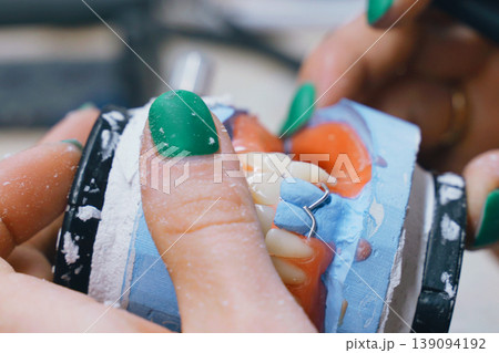Tech checks bite alignment on a denture model during work 139094192
