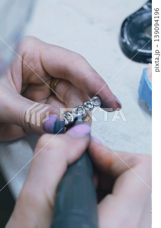 Crafting precision metal dentures by skilled dental technician in workshop Crafting precision metal dentures by skilled dental technician in workshop 139094196