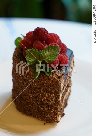 Decadent chocolate cake topped with fresh raspberries and mint leaf Decadent chocolate cake topped with fresh raspberries and mint leaf 139094204