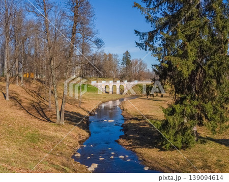 Stone bridge arches gracefully over a quiet stream Stone bridge arches gracefully over a quiet stream 139094614