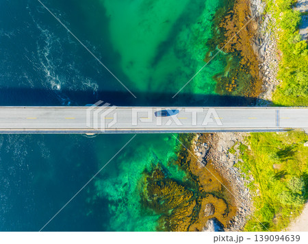 Aerial top down view of a car driving across a bridge over water. Aerial top down view of a car driving across a bridge over water. 139094639