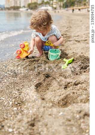 Toddler Playing With Beach Toys, Bucket And Shovel On Sunny Shoreline 139094785