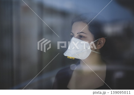 A woman staying at home in quarantine and watching the outside world through the window A woman staying at home in quarantine and watching the outside world through the window 139095011