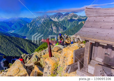 北アルプス 常念岳山頂の祠と休憩する登山者 穂高連峰と上高地を望む絶景 北アルプス 常念岳山頂の祠と休憩する登山者 穂高連峰と上高地を望む絶景 139095106