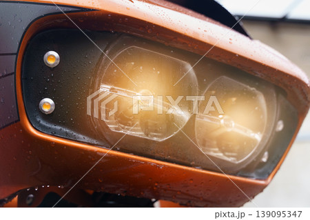 The included headlights of a motorcycle close-up, glowing yellow. The included headlights of a motorcycle close-up, glowing yellow. 139095347
