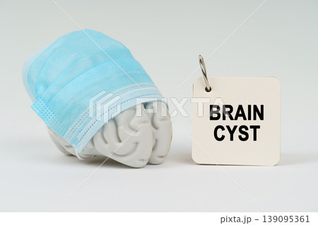 On a white surface next to the brain there is a notepad with the inscription - Brain Cyst On a white surface next to the brain there is a notepad with the inscription - Brain Cyst 139095361