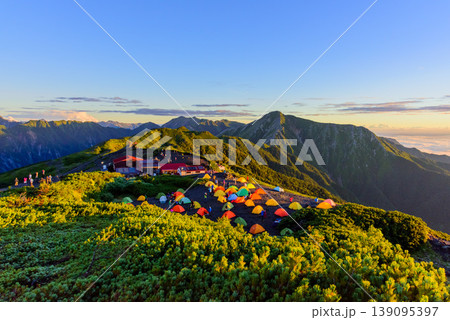 北アルプス 蝶ヶ岳ヒュッテの朝 朝日に輝く山々と絶景を楽しむ登山客たち 北アルプス 蝶ヶ岳ヒュッテの朝 朝日に輝く山々と絶景を楽しむ登山客たち 139095397