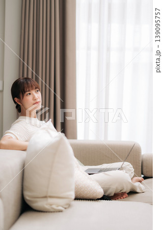 Peaceful asian woman sitting comfortably at home looking thoughtful taking relaxing break from working on an online business and studying modern technology Peaceful asian woman sitting comfortably at home looking thoughtful taking relaxing break from working on an online business and studying modern technology 139095757