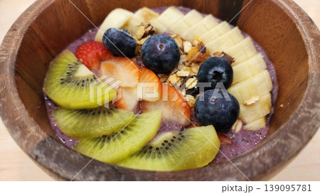 Healthy Acai Smoothie Bowl with Fresh Kiwi, Blueberries, Strawberry and Banana in Wooden Bowl Healthy Acai Smoothie Bowl with Fresh Kiwi, Blueberries, Strawberry and Banana in Wooden Bowl 139095781