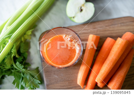 Carrot juice glass with celery and apples in kitchen healthy lifestyle concept 139095845