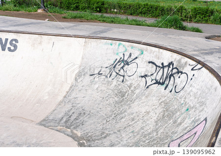 Empty concrete skatepark ramp with black graffiti tags 139095962
