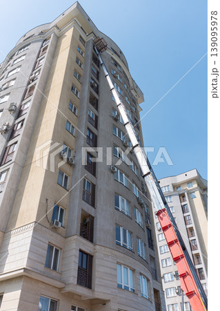 A large hydraulic lift extended to the top floor of a tall building 139095978