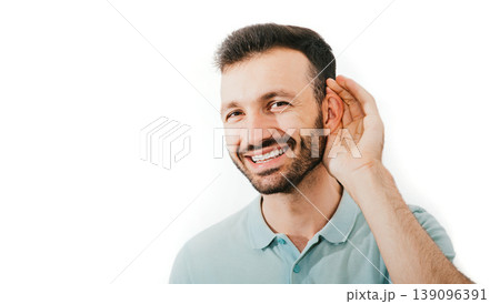 Check your hearing. Positive mixed race man holds his hand near his ear, isolated on a white background. Ear health, treatment and diagnosis of hearing Check your hearing. Positive mixed race man holds his hand near his ear, isolated on a white background. Ear health, treatment and diagnosis of hearing 139096391