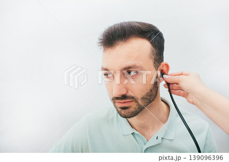 Mixed race man having a hearing test with special medical equipment. Impedance audiometry, tympanometry in a hearing center Mixed race man having a hearing test with special medical equipment. Impedance audiometry, tympanometry in a hearing center 139096396