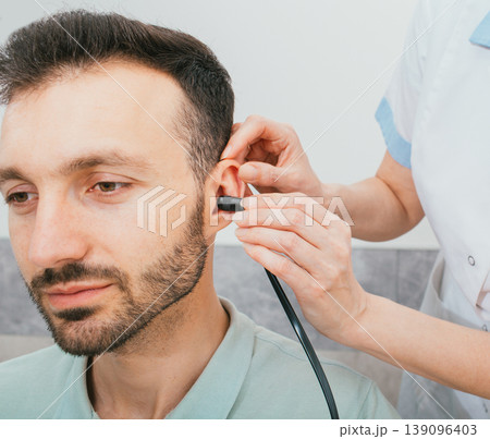 Mixed race man having a hearing test with special medical equipment. Impedance audiometry, tympanometry in a hearing center Mixed race man having a hearing test with special medical equipment. Impedance audiometry, tympanometry in a hearing center 139096403