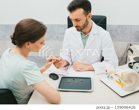 A young audiologist selects a hearing aid for a caucasian woman. Patient needs good hearing aids so that she can hear the sounds of the world. 139096426