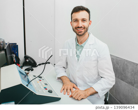 Portrait of a male audiologist in a modern hearing clinic during a hearing exam in a special audio room 139096434