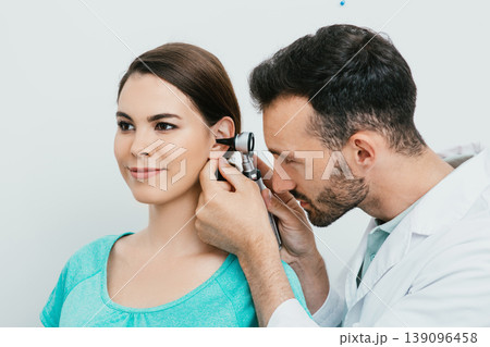 Otolaryngologist checking adult female ear using otoscope. Hearing exam for Hispanic woman. Otitis media, ear inflammation 139096458