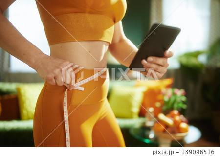 Digital Wellness Tracking: Woman Using Phone and Tape Measure Digital Wellness Tracking: Woman Using Phone and Tape Measure 139096516