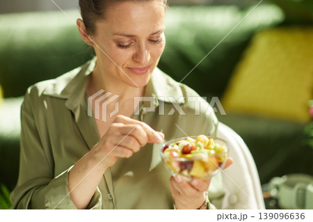 Smiling Woman Enjoying a Fresh Fruit Salad Snack Smiling Woman Enjoying a Fresh Fruit Salad Snack 139096636