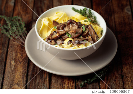 Noodles with mushrooms and thyme on a rustic wooden table. Noodles with mushrooms and thyme on a rustic wooden table. 139096867