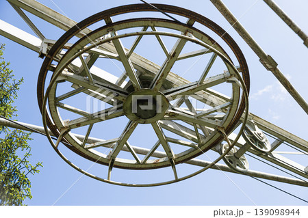 Weathered industrial pulley wheel against a clear blue sky 139098944