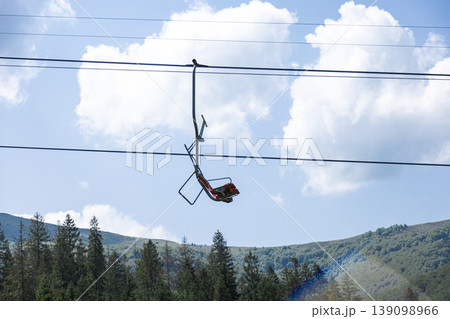 Empty Chairlift Suspended Over Green Mountains on a Sunny Day Empty Chairlift Suspended Over Green Mountains on a Sunny Day 139098966